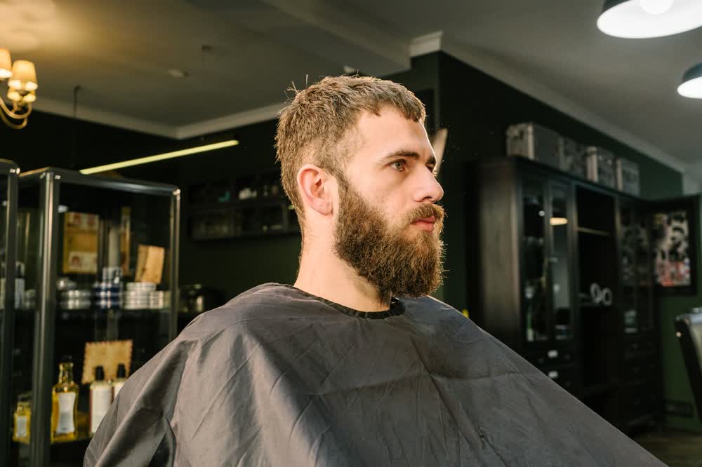 Klant met verzorgde baard in de barbershop-stoel
